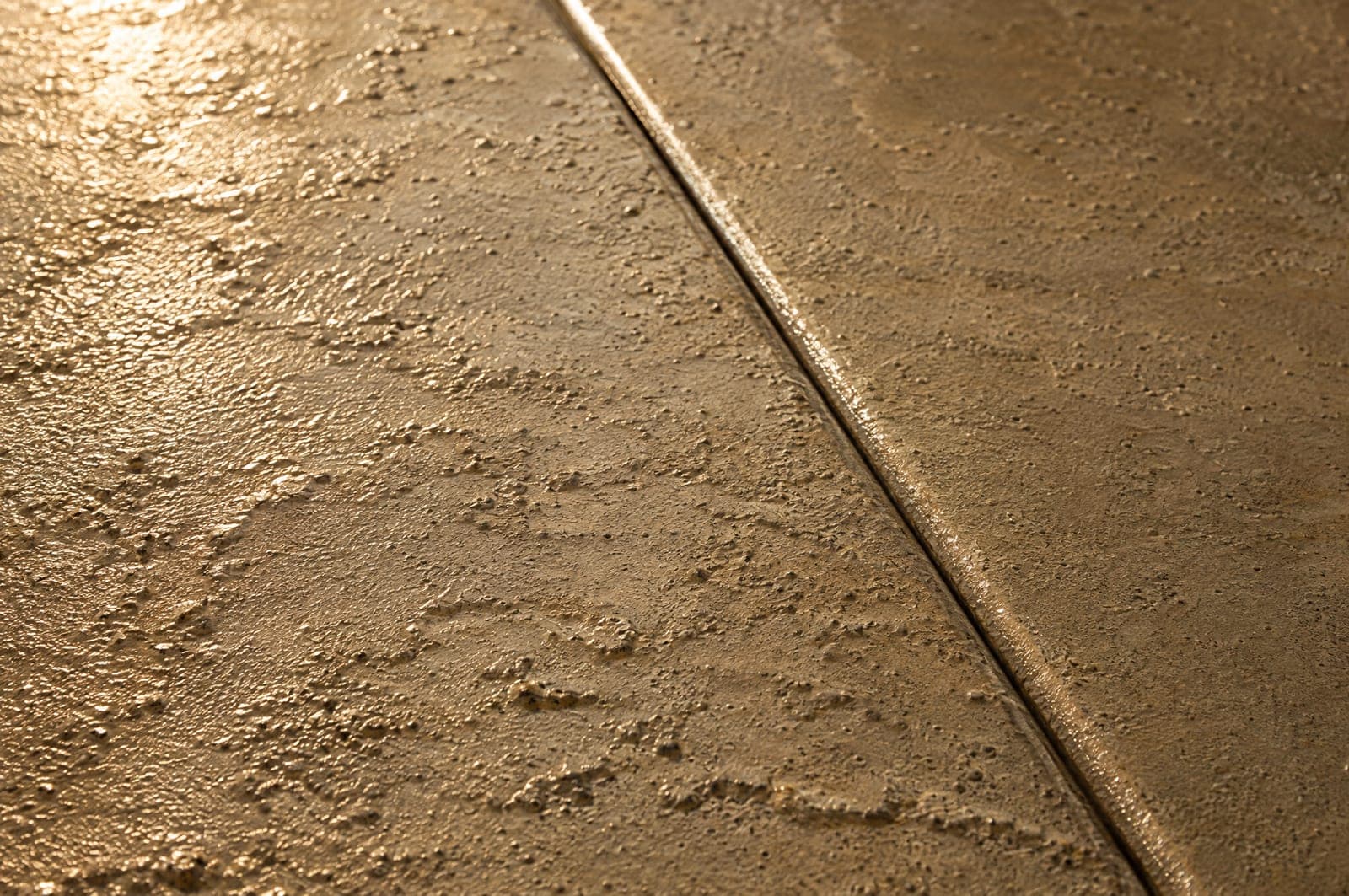 Close-up of a knockdown concrete overlay texture meeting a scored joint