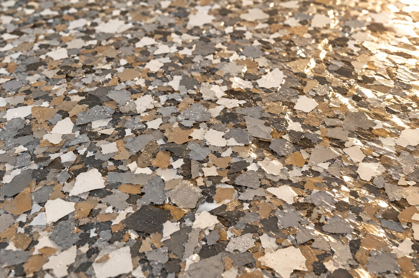 Close-up of gray, white and tan vinyl flake chips under a clear high-gloss topcoat
